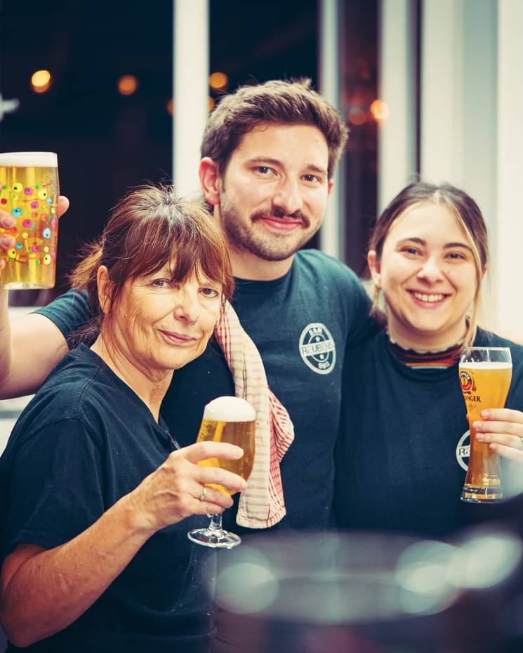 Three people in Reubens shirts raising their glasses